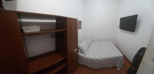 Un pequeño dormitorio con una cama y un pequeño armario en 2 quartos, completo com privacidade total, smarttv, Lapa, aeroporto, rodoviária , maracanã, metrô, etc, en Río de Janeiro