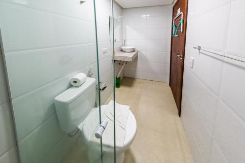 a bathroom with a toilet and a glass shower door at Pousada Maanaim Porto in Porto De Galinhas