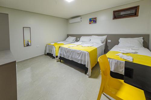 two beds in a room with yellow sheets at Pousada Maanaim Porto in Porto De Galinhas