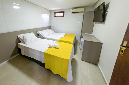 a small room with two beds and a television at Pousada Maanaim Porto in Porto De Galinhas