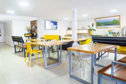 a dining room with wooden tables and yellow chairs at Pousada Maanaim Porto in Porto De Galinhas