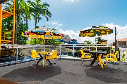 two tables and chairs with umbrellas on a patio at Pousada Maanaim Porto in Porto De Galinhas