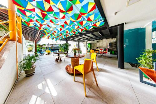 a room with a colorful ceiling and tables and chairs at Pousada Maanaim Porto in Porto De Galinhas