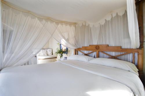 a white bed with white curtains in a bedroom at Beach Hotel Dos Mares in Tarifa