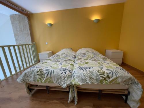 Ce lit se trouve dans une chambre dotée d'un mur jaune. dans l'établissement La Maison des Pressoirs, à Châteauvillain