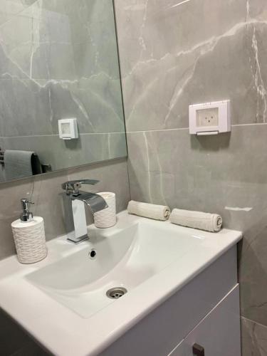 La salle de bains est pourvue d'un lavabo blanc et d'un miroir. dans l'établissement New 2 rooms flat fully equipped 5 min to Bat Yam beach near Tel Aviv, à Bat Yam