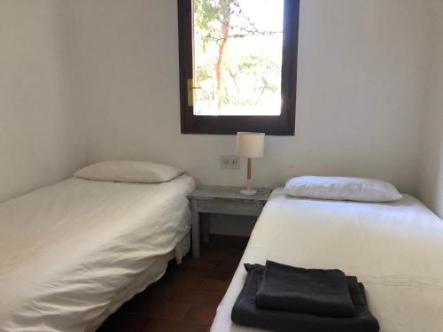 2 letti in una camera con tavolo e finestra di AZUL FORMENTERA a Es Pujols