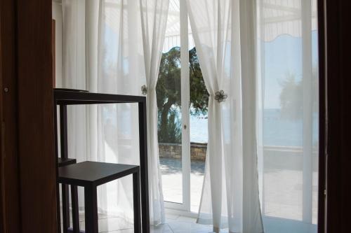 a chair sitting in front of a window with white curtains at Casa aMmare in Pioppi