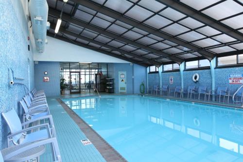 ein großer Pool mit Stühlen in einem Gebäude in der Unterkunft The Barclay Towers Hotel and Resort in Virginia Beach