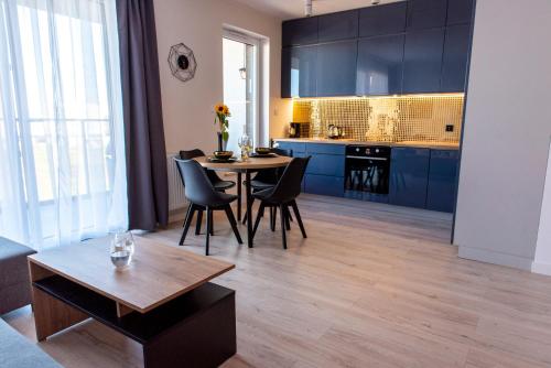 a kitchen and living room with a table and chairs at Marcelina Golden Apartments przy Aquapark Reda in Rumia