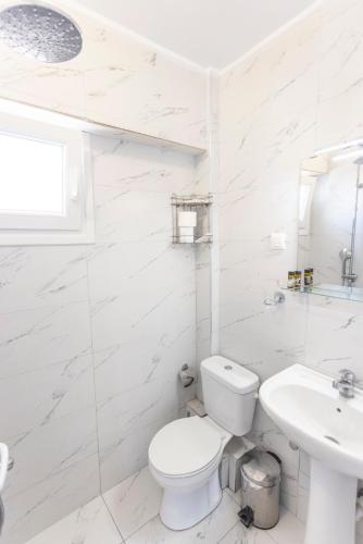 a white bathroom with a toilet and a sink at Apartment Duri in Pefkohori