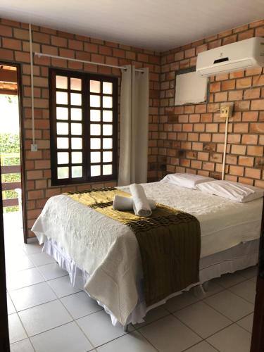 ein Schlafzimmer mit einem Bett und einer Ziegelwand in der Unterkunft Paraíso à beira mar, praia de Carapibús. Conde. João Pessoa in Conde