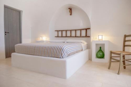 a white bedroom with a bed and a chair at Trulli sul Mare Forcatella in Savelletri di Fasano