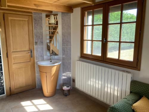 ein Bad mit einem Waschbecken neben einer Tür in der Unterkunft Charmante maisonnette indépendante in Broye
