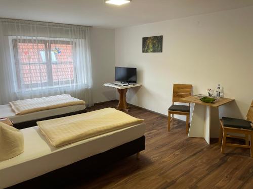Zimmer mit 2 Betten, einem Tisch und einem Schreibtisch in der Unterkunft Römercastell Wirtshaus & Hotel in Böhming