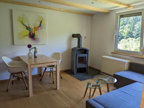 a living room with a table and a wood stove at Ruhiges Ferienhaus am Waldrand mit Sauna und Kamin in Langenbach