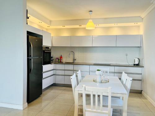 a kitchen with a white table and white chairs at Royal Aparatment on the Sea , Blvd Nitza 34 in Netanya