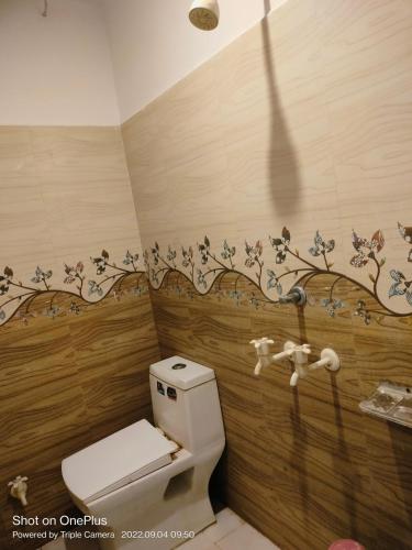 a bathroom with a toilet with a flower mural on the wall at Hotel Ayodhya Palace in Farrukhābād