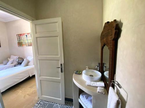 a bathroom with a sink and a mirror and a bed at Villa Diaf Johanne in Aït Ourir