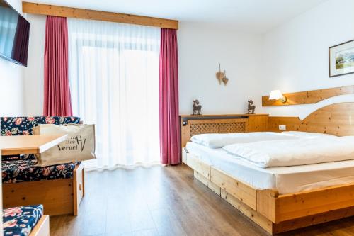 a bedroom with two beds and a desk and a window at Hotel Vernel in Santa Cristina in Val Gardena
