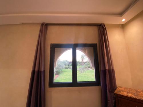 a window in the corner of a room with curtains at Villa Diaf Johanne in Aït Ourir