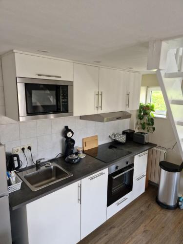 a kitchen with white cabinets and a sink at Maisonnette Slijkplaat 18 in Hoofdplaat