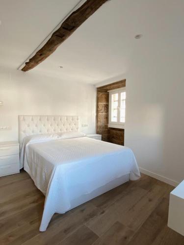 a white bedroom with a white bed and a window at Celanova House in Celanova