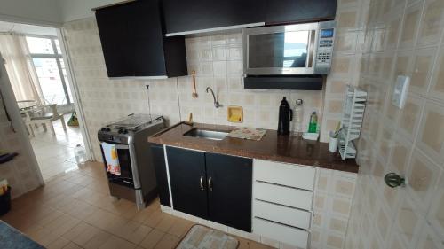 a small kitchen with a sink and a microwave at Cobertura Com Vista Para a Praia in São Vicente