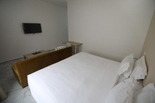 a bedroom with a white bed and a television at MJI GROUP in Tan-Tan