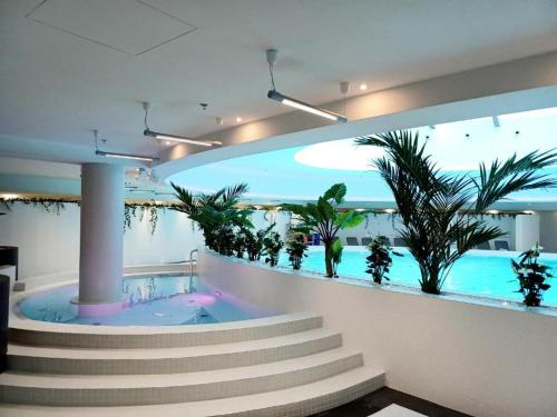 a room with a swimming pool with stairs and plants at Luksusowy apartament z widokiem, basenem i sauną Hanza Tower Szczecin in Szczecin