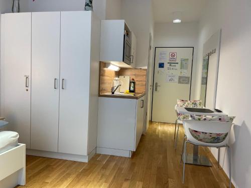 a kitchen with white cabinets and a table and a chair at Myroom Business Apartment Nähe Messe München in Munich