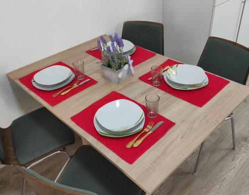 a wooden table with white plates and red napkins at 2 Zimmerwohnung in Bietingen in Gottmadingen