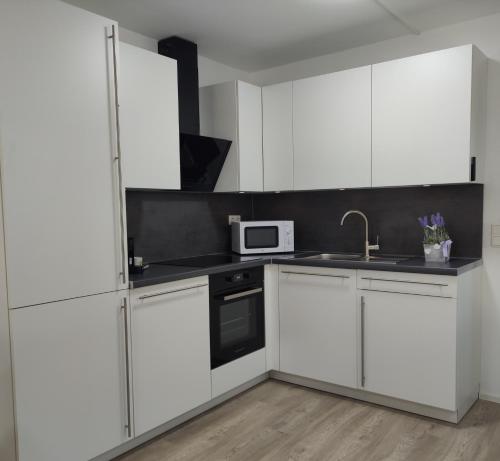 a white kitchen with white cabinets and a microwave at 2 Zimmerwohnung in Bietingen in Gottmadingen