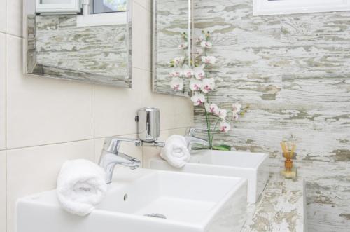 bagno bianco con lavandino e specchio di Paradise Resort ad Akrotírion