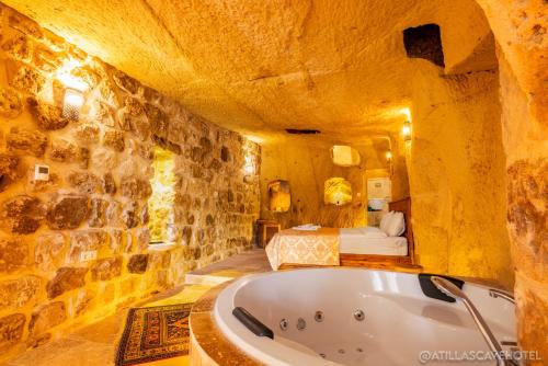a large bathroom with a tub in a stone wall at Atilla's Cave Hotel in Nevsehir