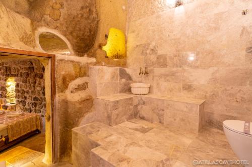 a stone bathroom with a tub and a toilet at Atilla's Cave Hotel in Nevsehir