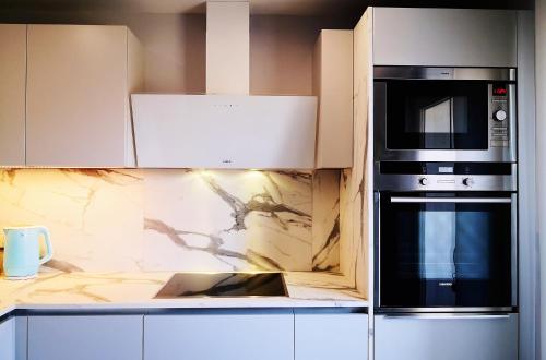 una cucina con armadietti bianchi e forno a microonde nero di Superbe cosy T1 Bis Studio 40m2 indépendant en maison avec parking gratuit a Caluire-et-Cuire