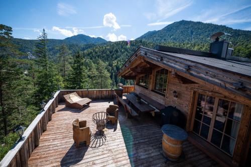 une terrasse en bois avec un banc et une maison dans l'établissement Alpe Chalets Goldener Hirsch, à Scharnitz