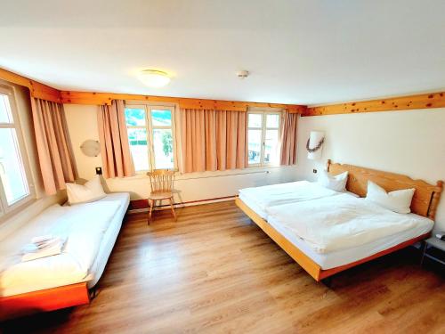 two beds in a room with wooden floors and windows at Hotel Sternen Unterwasser in Unterwasser