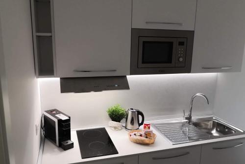 a white kitchen with a sink and a microwave at Dimore Capirro Charming Family House in Trani