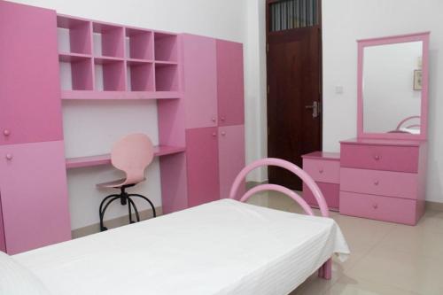 a pink room with a bed and a mirror at Arazia in Panadura