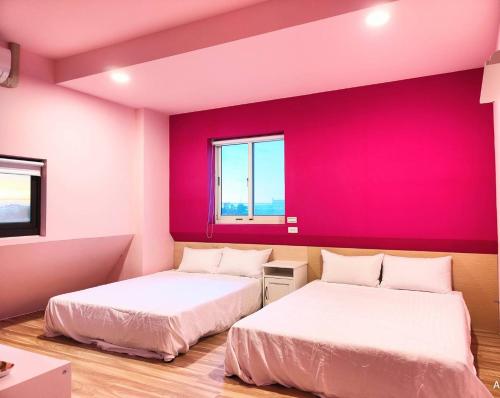 two beds in a room with a red wall at Xinyuanbao Shangshi Homestay in Donggang