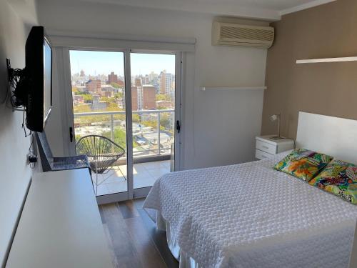 1 dormitorio con cama, TV y balcón en BALCÓN AL RíO PARANÁ en Paraná