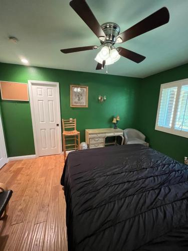 a bedroom with green walls and a bed with a ceiling fan at Beautiful Foothill Living in Rancho Cucamonga