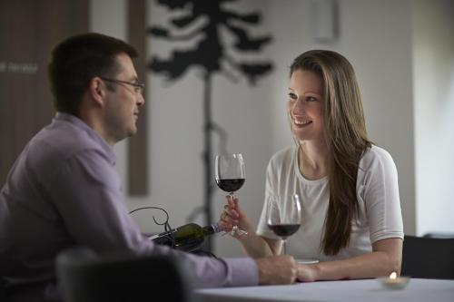 a man and woman sitting at a table with a glass of wine at Hotel Therapia in Pécs
