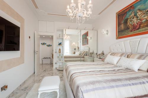 ein weißes Schlafzimmer mit einem großen Bett und einem Kronleuchter in der Unterkunft Suite La Fenice in Bergamo