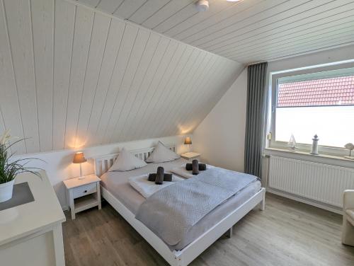 a white bedroom with a bed and a window at Das Inselhaus in Norddeich
