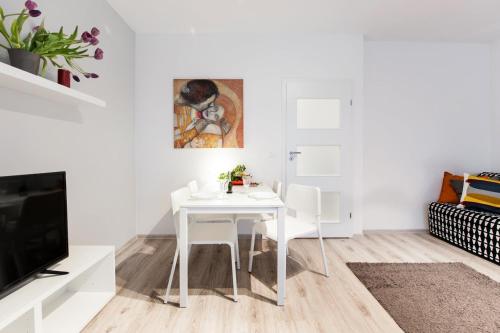 une salle à manger blanche avec une table et une télévision dans l'établissement Project Comfort Apartament Dywizjonu 303 175/8 Warszawa, à Varsovie