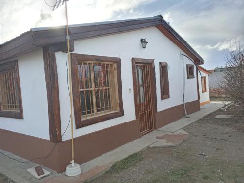 un pequeño edificio blanco con ventanas de madera y una calle en Mi Refugio en Río Gallegos