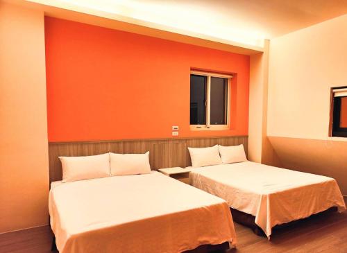 two beds in a room with orange walls at Xinyuanbao Shangshi Homestay in Donggang